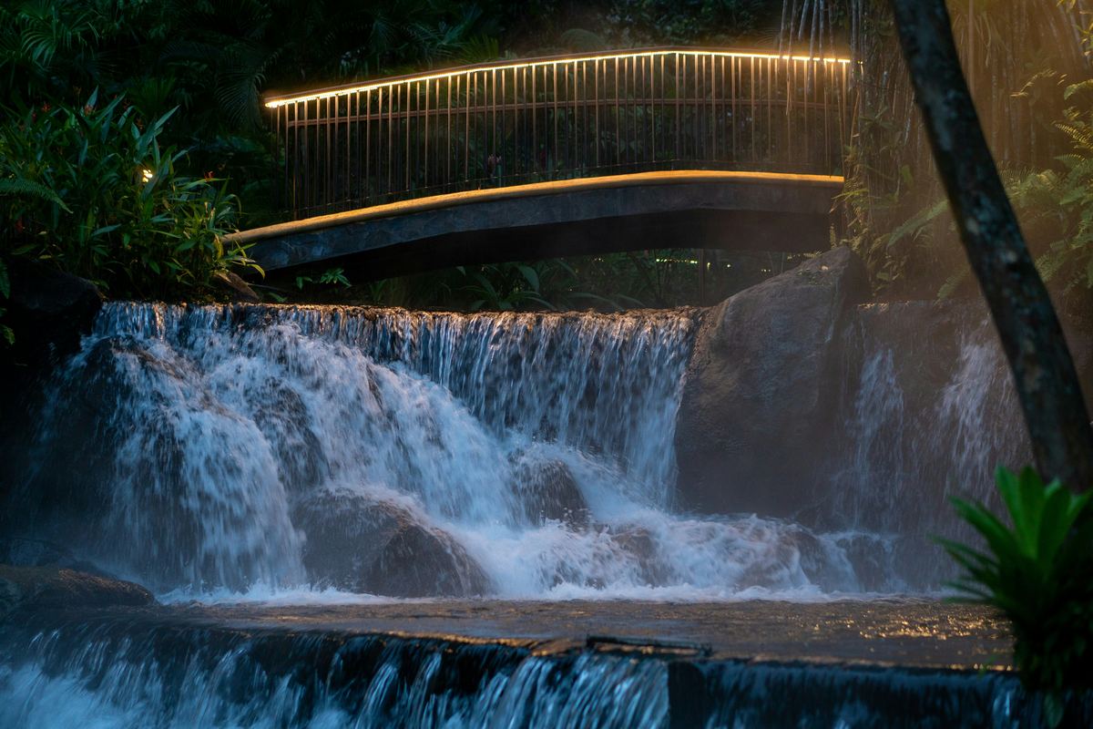Illuminated hot springs and bridge at night in La Fortuna, Costa Rica